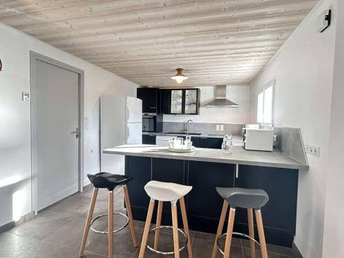 une cuisine avec deux tabourets de bar et un comptoir dans l'établissement Maison neuve près des dunes avec jardin clos, 3 chambres et tout confort, à 800m de la plage - FR-1-224B-548, à Barbâtre