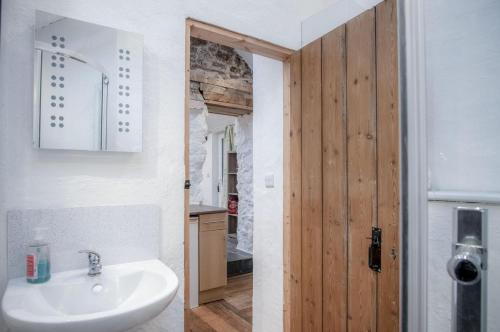 a bathroom with a sink and a wooden door at The Anchor Light - 1 Bed - Freshwest Beach Retreat in Pembroke