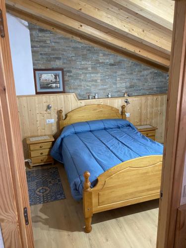 a bedroom with a wooden bed with blue sheets at Casa Casteller in Arfa