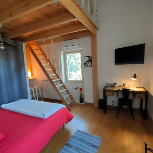 a bedroom with a bed and a desk and a staircase at Le Mas du Coquelicot in Dions