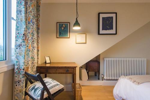 ein Schlafzimmer mit einem Schreibtisch, einem Bett und einer Treppe in der Unterkunft Shell Seekers Cottage in Deal