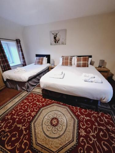 two beds in a room with a red rug at The First & Last Inn in Eyemouth