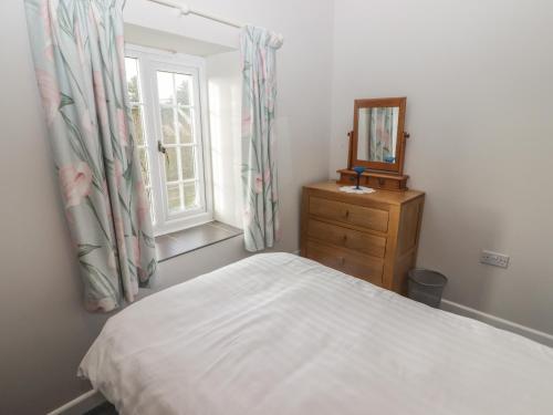 a bedroom with a bed and a mirror and a window at The Granary in Kilgetty