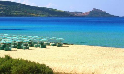 a beach with chairs and umbrellas and the ocean at Villa Veronica in Sedini