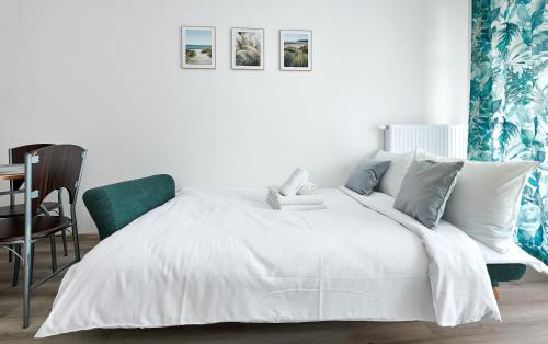 1 dormitorio con 1 cama blanca y 1 silla en Poznań Airport Comfy Apartment en Poznan