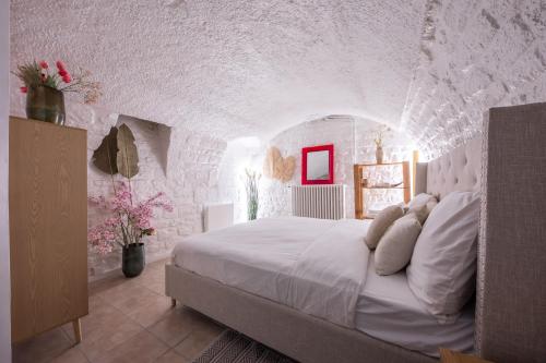 een slaapkamer met een wit bed in een stenen muur bij LOUVRE-MONTORGEUIL PARIS HISTORICAL CENTER in Parijs