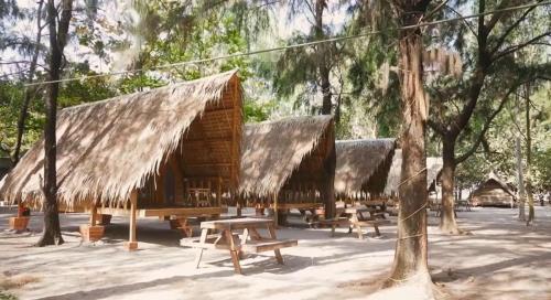un grupo de cabañas de madera con bancos y árboles en Cabin in San Narciso, en San Narciso