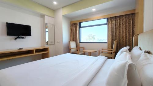 een hotelkamer met een bed en een televisie bij The Sky Imperial Hotel The Maison in Anand