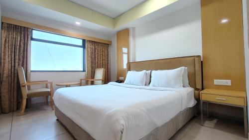 een hotelkamer met een groot bed en een raam bij The Sky Imperial Hotel The Maison in Anand