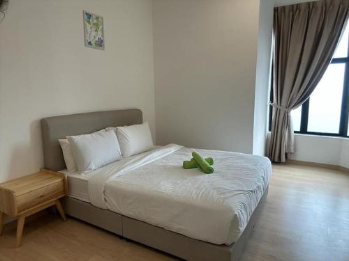 a bed with a green stuffed animal sitting on it at Mutiara Melaka Beach Resort by Ally 