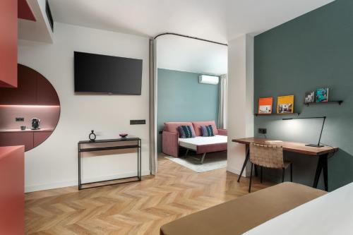 Habitación con cama, escritorio y TV. en Aparthotel Tribunal, en Madrid