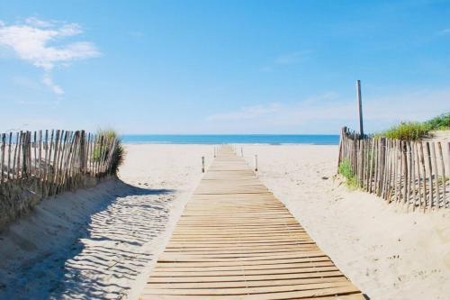 een houten pad naar het strand met de oceaan op de achtergrond bij Le Terrasse en Mer- Air conditioning parking and seaside! in Palavas-les-Flots