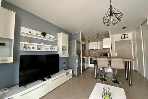 een woonkamer met een grote televisie en een keuken bij Le Terrasse en Mer- Air conditioning parking and seaside! in Palavas-les-Flots