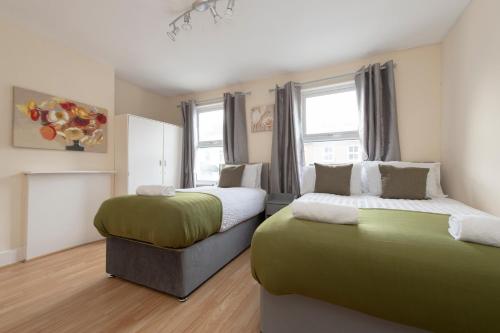 Kentにある4 BED House IN Dartford 8 Beds Sleeps 10のベッドルーム1室(ベッド2台、緑と白のシーツ付)