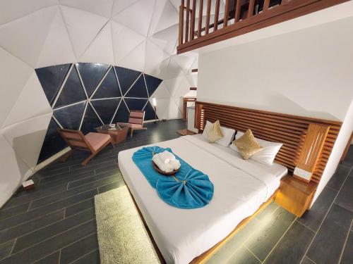a bedroom with a large white bed with blue sheets at GeoLux - Luxurious Geodesic Dome in Chikmagalur