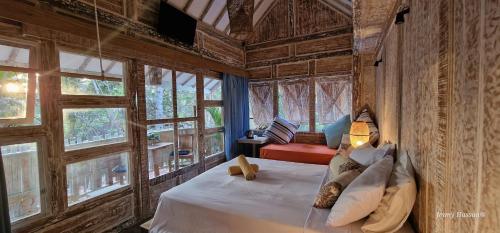 um quarto com uma cama num quarto com janelas em Villas Light House - Eco-Traditional Joglo em Gili Trawangan