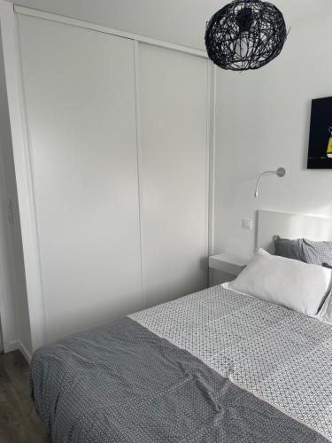a white bedroom with a bed with a large headboard at La maison Ti Billou in Santec