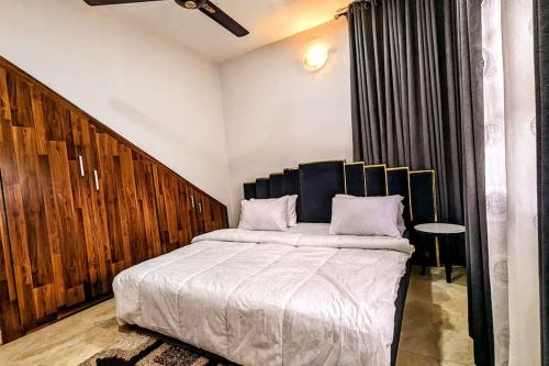 Schlafzimmer mit einem großen Bett mit einem Kopfteil aus Holz in der Unterkunft The Zen Haven in Uyo