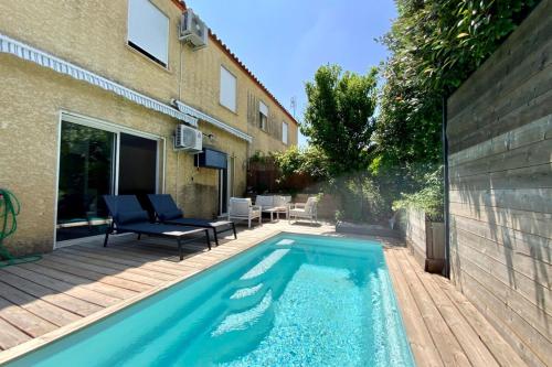 - une piscine en face d'une maison avec une terrasse dans l'établissement Le Lovely - Appartement avec clim et piscine !, à Le Crès