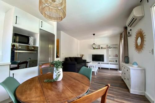 una sala da pranzo e un soggiorno con tavolo e sedie di Le Lovely - Appartement avec clim et piscine ! a Le Crès