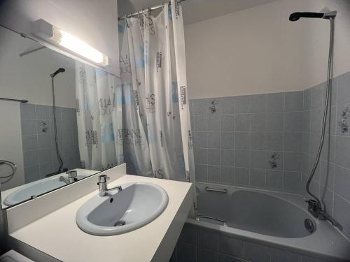 y baño blanco con lavabo y bañera. en 514 - Appartement 1 chambre vue mer en bordure de la plage du centre d'Erquy, en Erquy