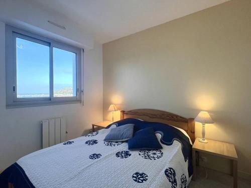 Un dormitorio con una cama con almohadas azules y una ventana en 514 - Appartement 1 chambre vue mer en bordure de la plage du centre d'Erquy, en Erquy