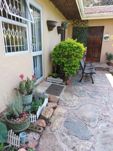 a patio with a bench and plants in front of a house at Shady Glade in Hillcrest