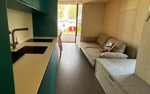 ポダースドルフ・アム・ゼーにあるMOBILE HOMES direkt am Strand des Neusiedler Seesの小さなリビングルーム(ソファ付)、キッチンが備わります。
