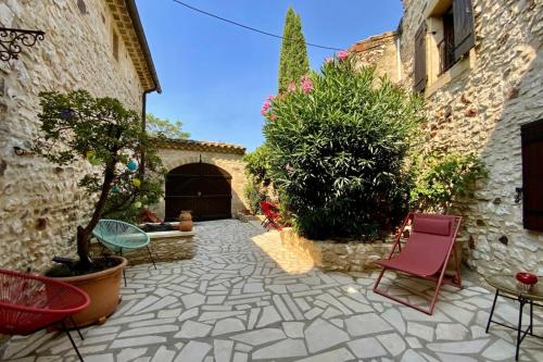 une cour avec des chaises et des plantes dans un bâtiment dans l'établissement L'Uzétienne- Large residence with pond and patio!, à Pouzilhac