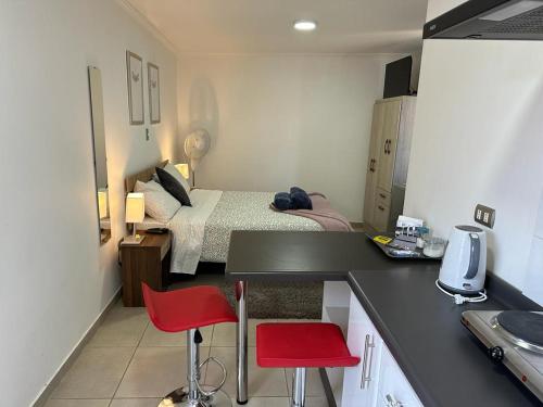 Cet appartement comprend une chambre avec un lit et une cuisine avec des chaises rouges. dans l'établissement Departamento Merced, à Quillota
