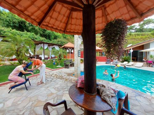 a man and a woman standing in front of a swimming pool at Pousada Pompeia in Socorro
