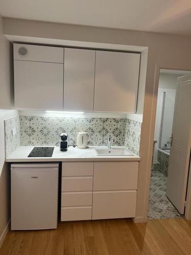 une cuisine avec des armoires blanches et un évier dans l'établissement So Paris Group - Fully Serviced Apartment - Jardin des Plantes - Heart of Paris, à Paris