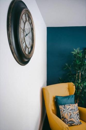 un reloj colgando en una pared junto a una silla amarilla en Sapphire Lodge-Wyndale-WContractors Parking, en Birmingham
