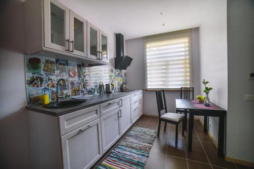 a kitchen with white cabinets and a table with a dining room at Studio apartment in private house in Riga