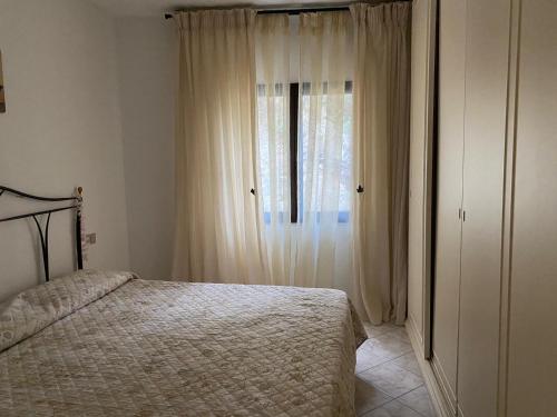 Schlafzimmer mit einem Bett und einem Fenster mit Vorhängen in der Unterkunft Il belvedere in Budoni