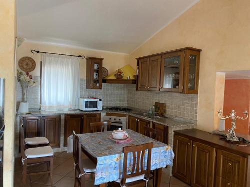 eine Küche mit Holzschränken und einem Tisch mit Stühlen in der Unterkunft Il belvedere in Budoni