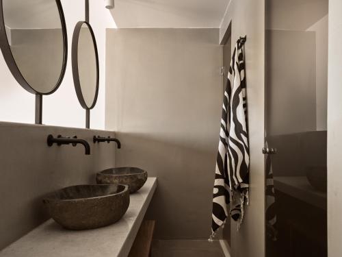 a bathroom with two sinks and two mirrors at Seaside A Lifestyle Resort - Adults Only in Agia Pelagia
