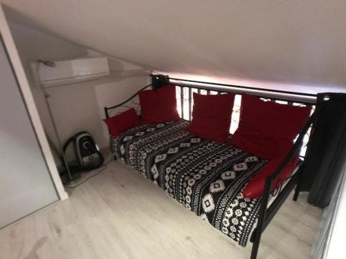 Una cama con almohadas rojas en una habitación pequeña. en Villa Port Leucate, 1 pièce, 5 personnes - FR-1-81-444 en Port Leucate