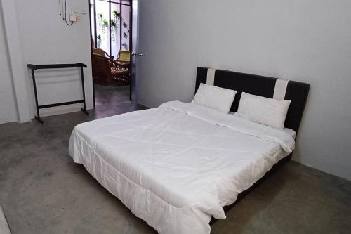 - un lit avec des draps et des oreillers blancs dans l'établissement Cozy Nature Homestay - ADS Printing, à Nibung Tebal
