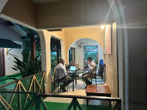 two men sitting at a table with a laptop at Green Villa in Oluvil
