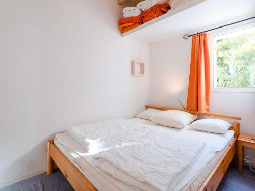 - une petite chambre avec un lit et un rideau orange dans l'établissement Pavillon Climatisé 3 Pièces avec Piscine, Terrasse, Parking, et Télévision - 4 Couchages - FR-1-409-3, à Narbonne-Plage
