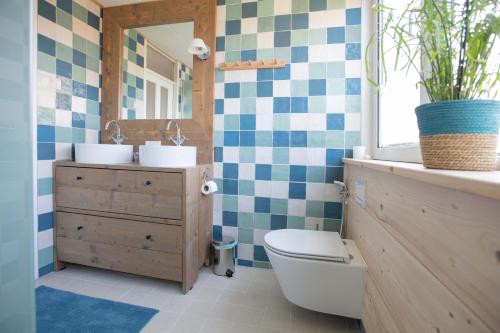 a bathroom with a toilet and two sinks and a mirror at Vegan B&B De Groene Mus in Wervershoof