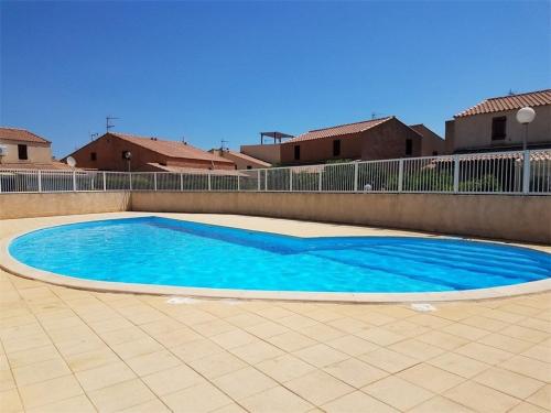 une grande piscine bleue sur un patio carrelé dans l'établissement Villa 3 pièces avec piscine, terrasse et parking privé - 4 personnes, animaux acceptés - FR-1-409-20, à Gruissan