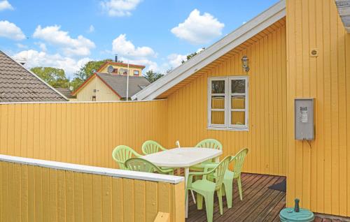 a yellow house with a table and chairs on a deck at Two-Bedroom Holiday Home In Hemmet in Hemmet