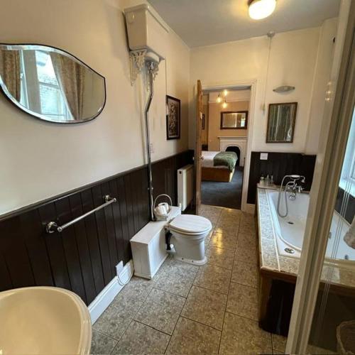 a bathroom with a toilet and a tub and a sink at The Old Registry guest house in Haworth
