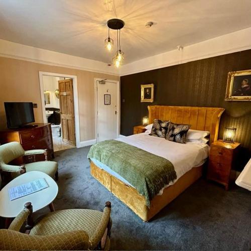 a bedroom with a large bed and a chair at The Old Registry guest house in Haworth