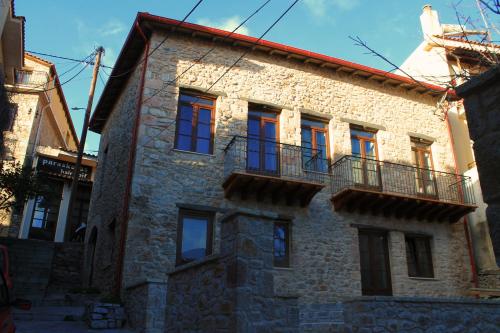Casa de piedra con ventanas rojas y balcón. en Δρυάδες Suites, en Arachova
