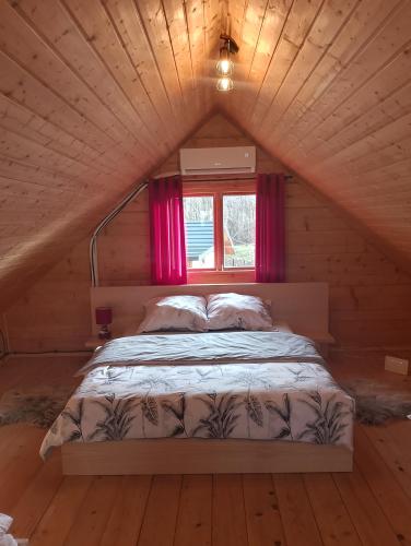 a bed in a wooden room with a window at Siedlisko Sielska Dolina Nad Stawem luksusowy domek całoroczny z klimatyzacją 
