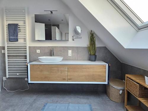 La salle de bains mansardée est pourvue d'un lavabo et d'un miroir. dans l'établissement Familienurlaub im Haus Seeglück, à Wangerland