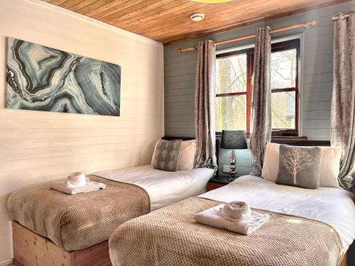 a room with two beds and a painting on the wall at Goldcrest 1-Hot Tub-Woodland Lodges-Carmarthenshire-Tenby in Carmarthen